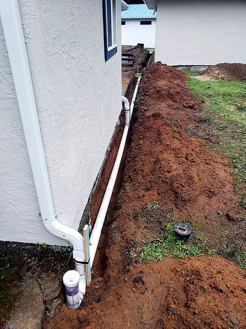 Drainage trench and downspout line dug alongside a home by SeaBreeze